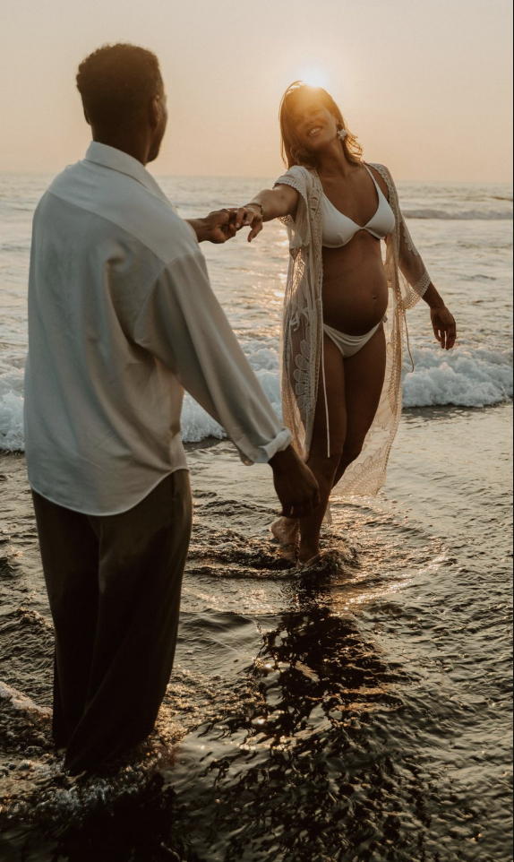 Séance grossesse en couple sur la plage au coucher du soleil